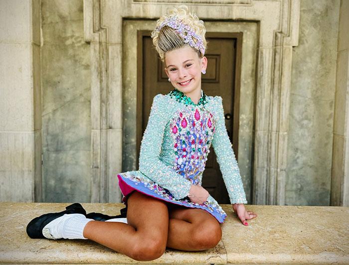Nemours patient Kieva sits smiling in her Irish dancing costume