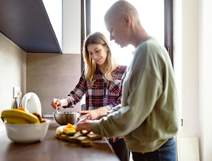 A bald female cancer patient prepares a healthy meal