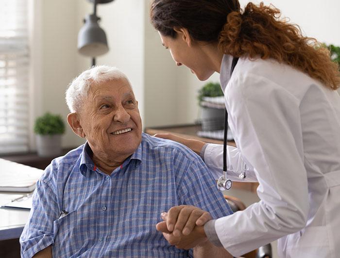 Stock image of elderly man smiling up at female health worker