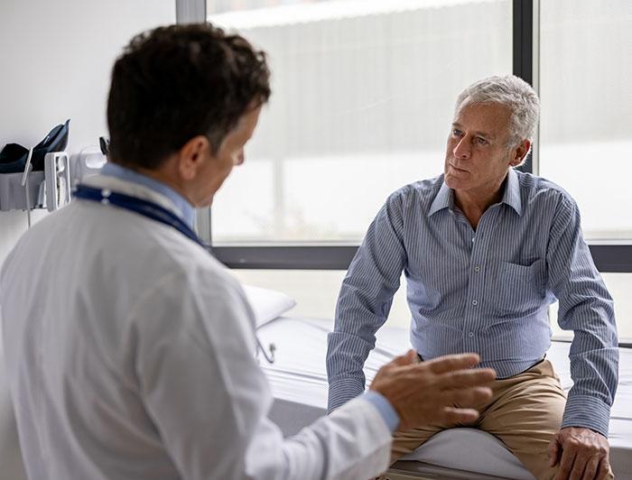 A male physician and older male patient sit talking