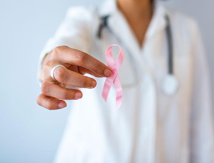 Stock photo of anonymous female physician holding a pink breast cancer ribbon