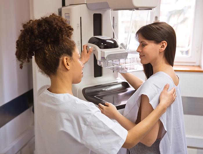 A patient is escorted to a mammogram machine