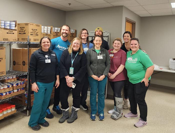 Avera Health team stands in front of food pantry shelves
