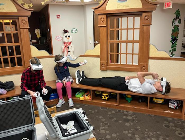 Children sit in a playroom wearing VR headsets