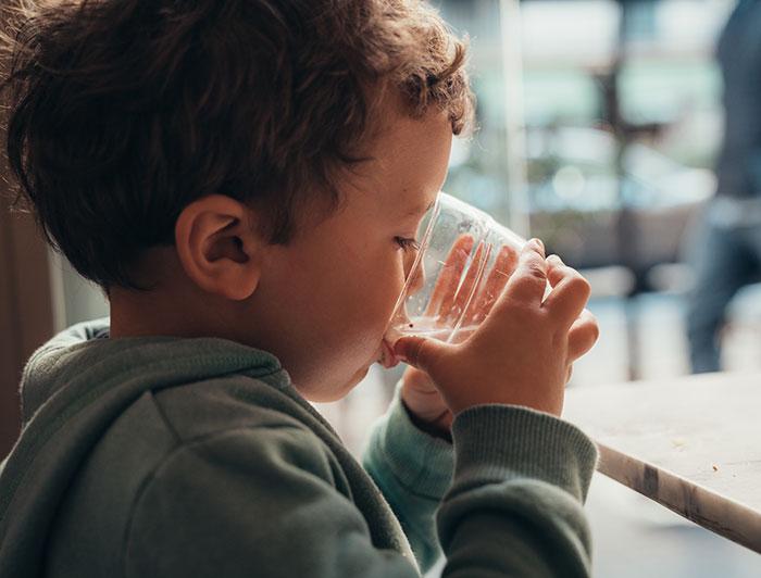 A toddler drinks water from a cup