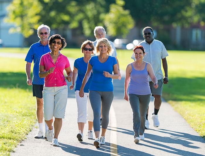 A diverse group of older people walk together on an outdoor fitness track