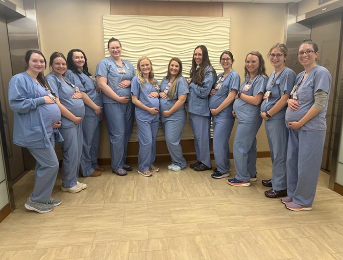 St. Vincent nurses stand in a row wearing matching scrubs, hands on their pregnant bellies
