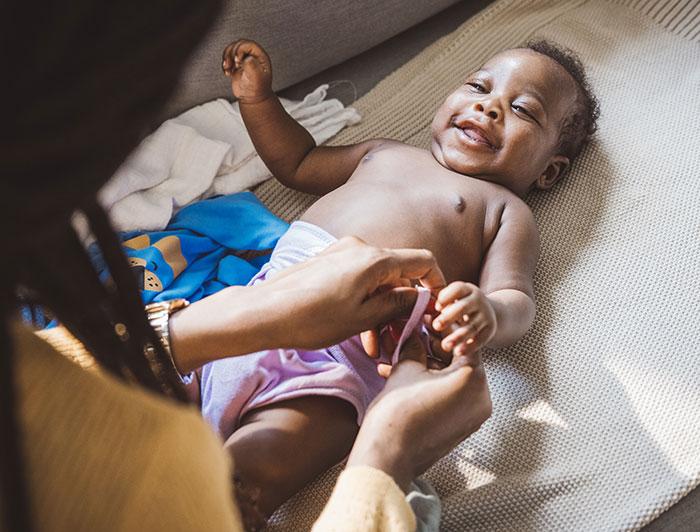 A woman puts a diaper on a baby