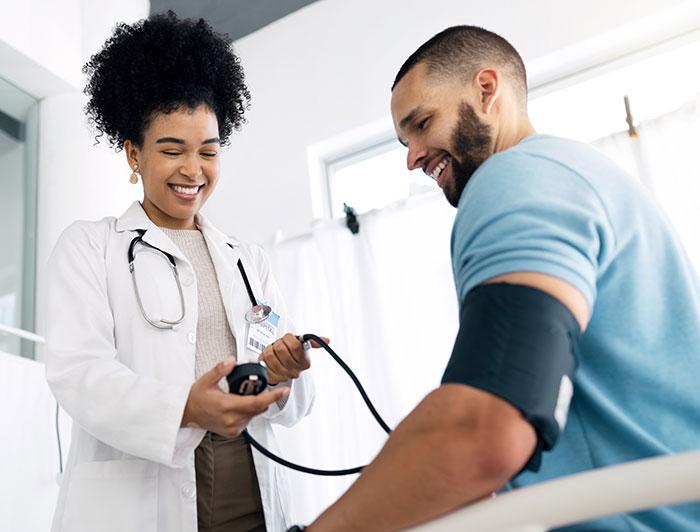 A female health worker checks a young man's blood pressure