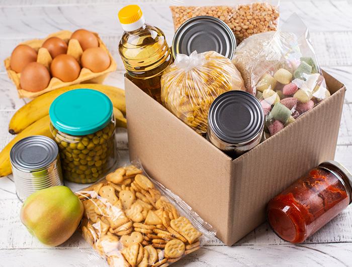Stock image of canned goods, dry goods and fruit in a cardboard box
