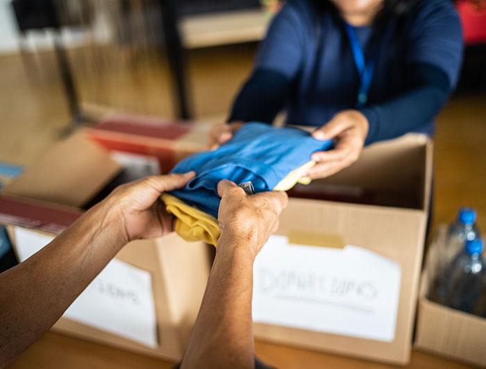 Stock photo of outstretched hands receiving clothing donations